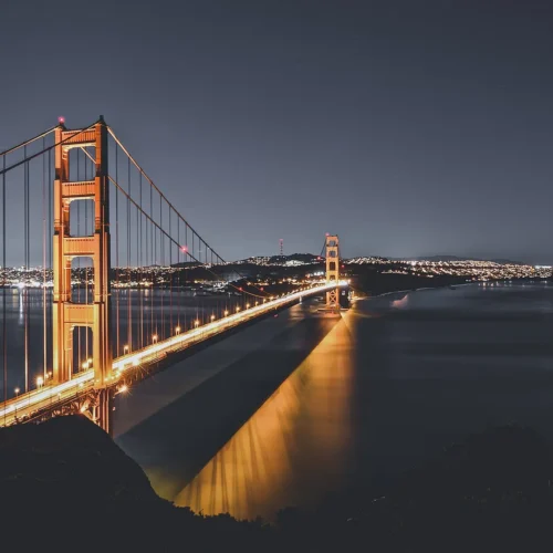 Golden Gate Bridge illuminated above San Francisco Bay at dusk.