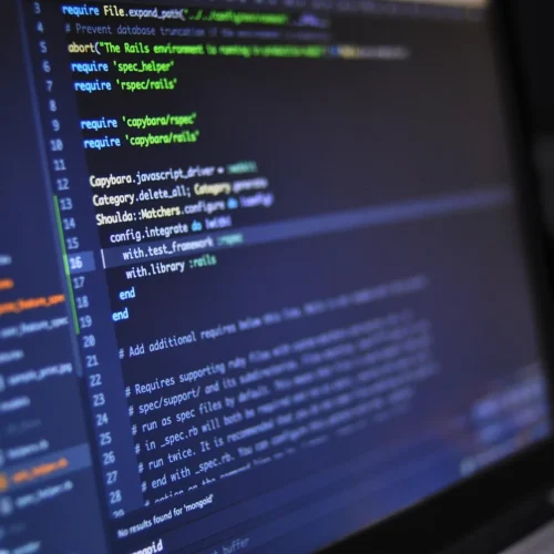 Computer screens displaying programming code in a technology workspace.