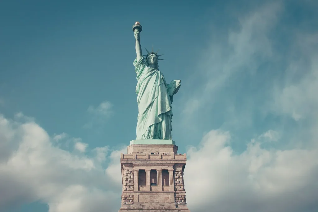 Statue of Liberty overlooking New York Harbor beneath a blue sky.