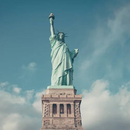 Statue of Liberty overlooking New York Harbor beneath a blue sky.