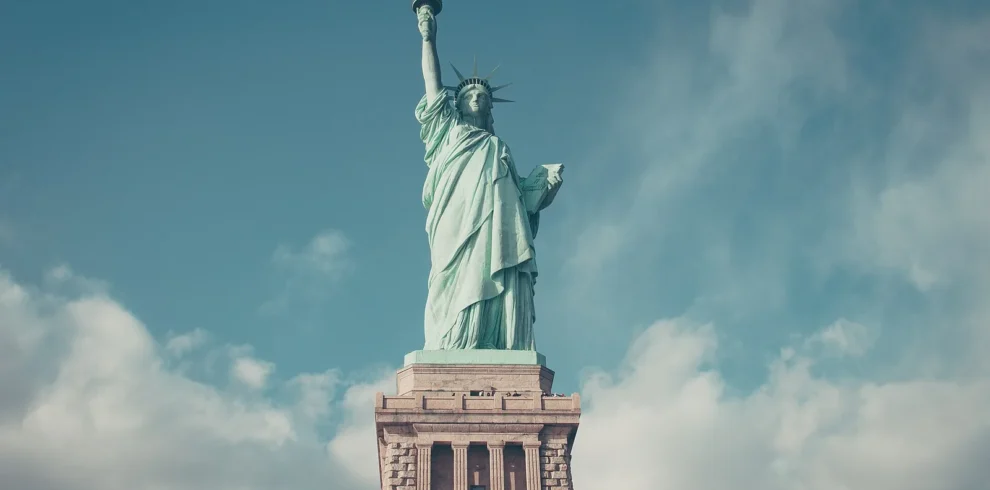 Statue of Liberty overlooking New York Harbor beneath a blue sky.