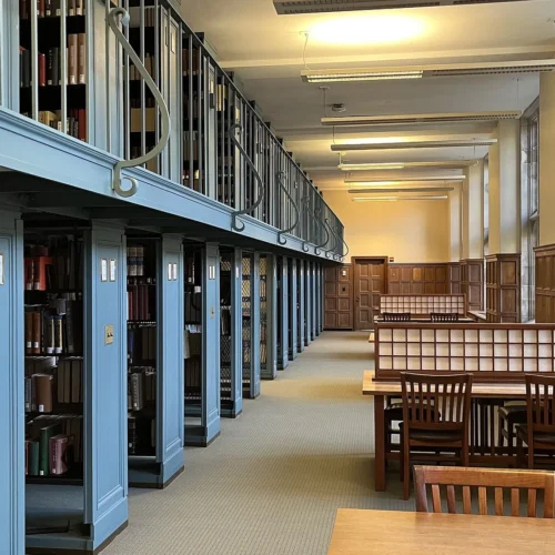 Quiet university library reading room with study tables and shelves.