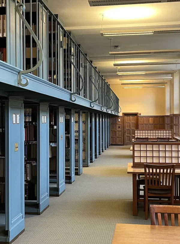 Quiet university library reading room with study tables and shelves.