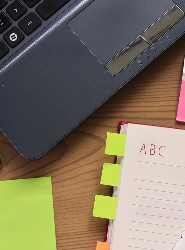 Notebook, pen and laptop arranged on a desk for writing and planning.