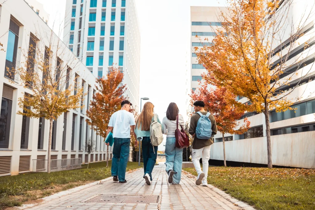 Students walking between modern university buildings in autumn.