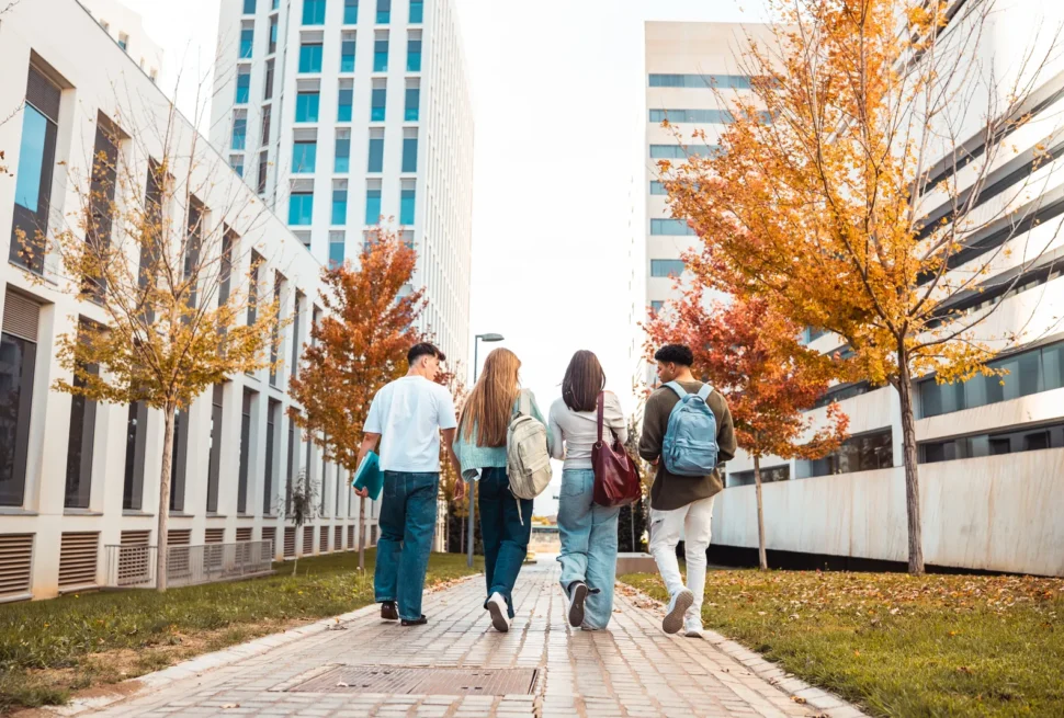 Students walking between modern university buildings in autumn.