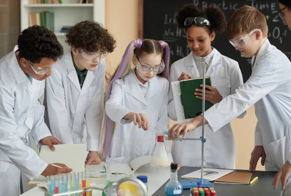 Students wearing lab coats and safety glasses working on a science experiment.