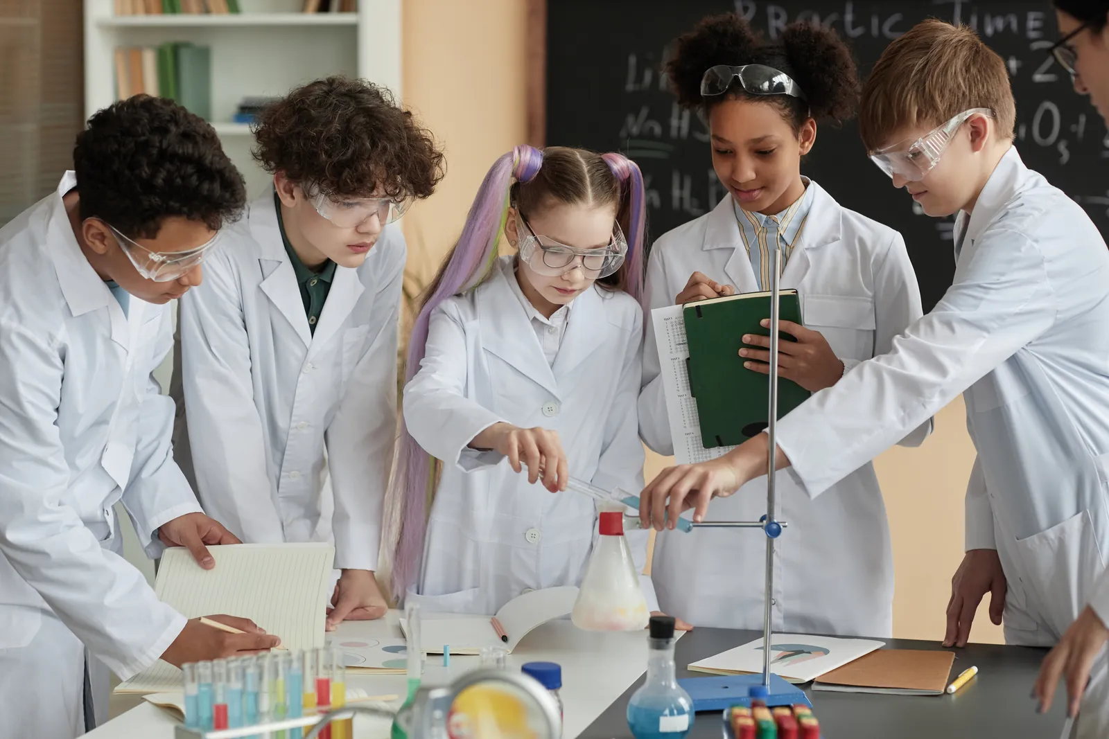Students wearing lab coats and safety glasses working on a science experiment.