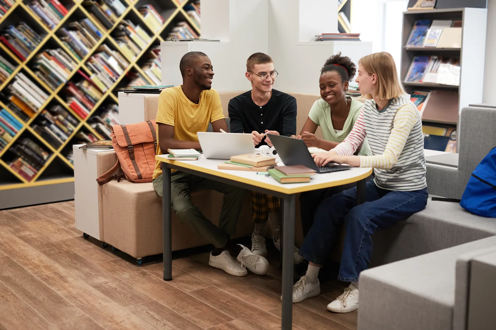 Young adults discussing their work around a library table.