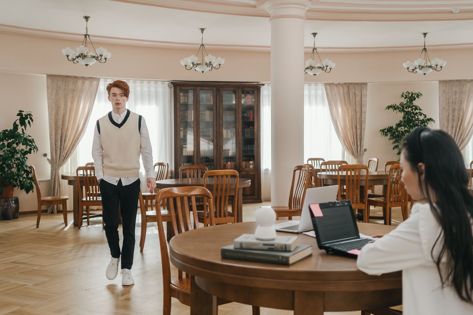 People studying at tables in a bright university library.